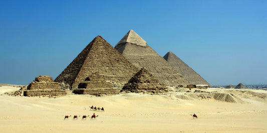 Pyramids of Giza with camels in the foreground under a clear blue sky